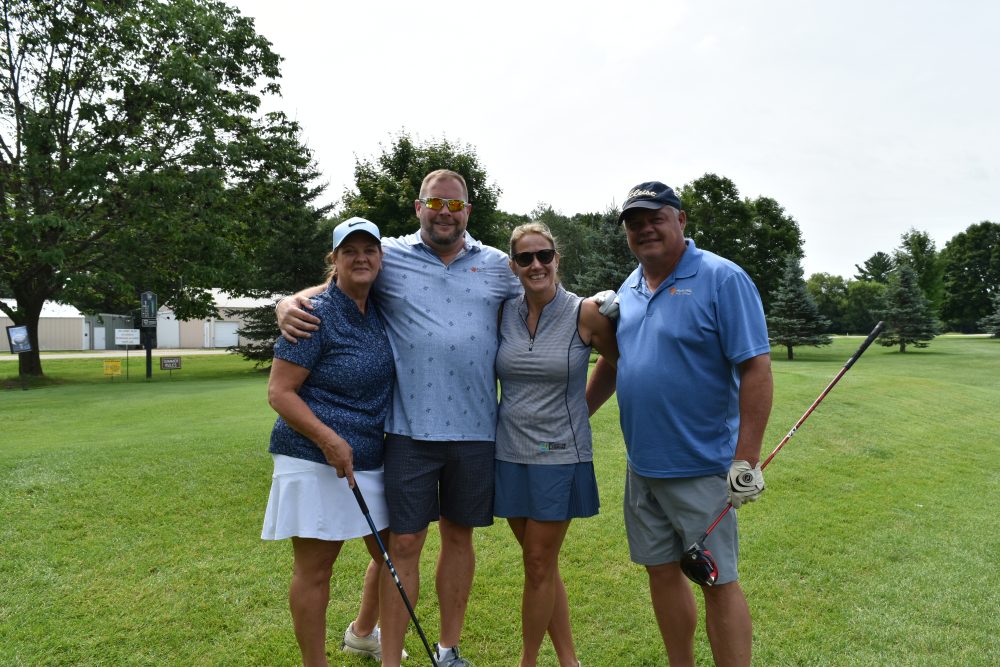 Group of four golfers posing for photo